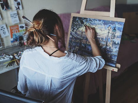 A woman painting on canvas in front of an easel.